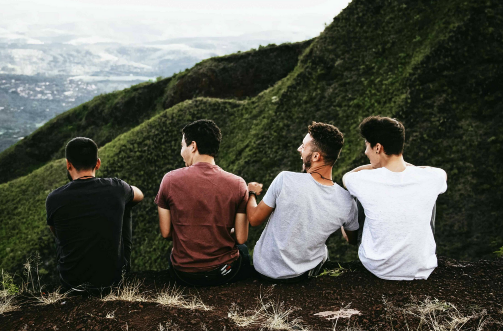four men sitting together on a mountain